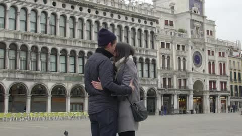 A Couple Hug In Front Of An Architectural Building