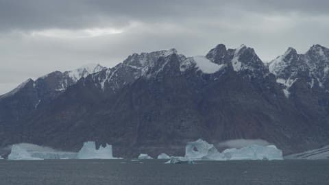 A Distant View Of Snow Capped Mountains And Icebergs