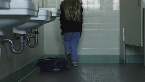 A Little Girl Throws Her Backpack Down In A Public Restroom Then Sits On The Floor In The Corner