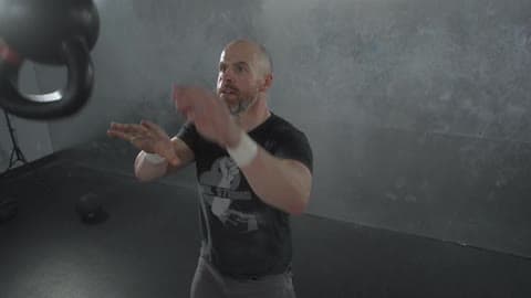 A Man Swinging And Flipping A Kettlebell