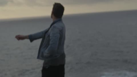 A Man Throws A Rock Towards The Ocean