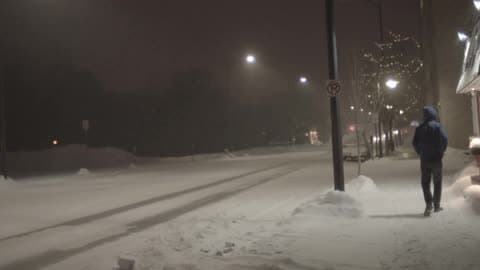 A Man Walks Down A Snowy City Road