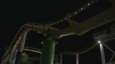 A Roller Coaster Moves Along A Track At Night