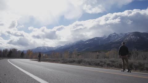 Cloudy Day As A Man Rides His Skateboard Down A Road