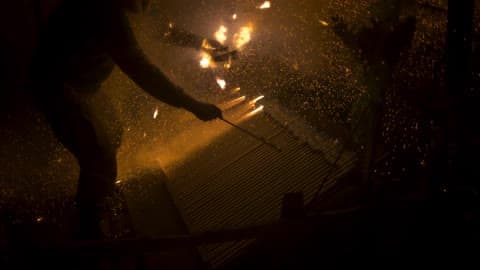 Flames Sparking As A Person Stands Over It In The Dark