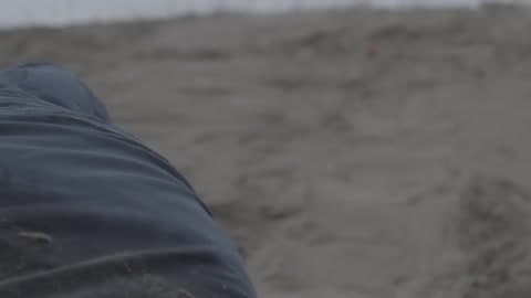 Man Crawling Up A Sandy Hill On A Cloudy Day