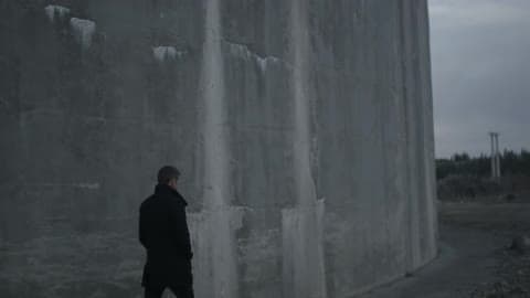Man Walking Alongside A Tall Wall Of Stone