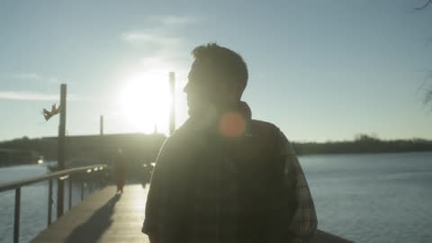 The Sun Shines On A Man Standing On A Pier