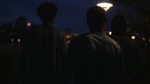 Young Men Walking Down The Street In An Urban Area Next To The Water